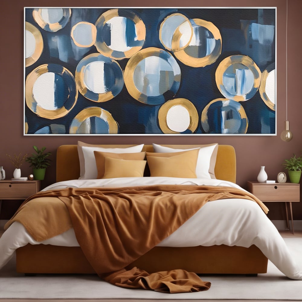 Tablou canvas cu pictura abstracta cu cercuri albastre si aurii, in rama de aluminiu argintiu, pe perete intr-un dormitor